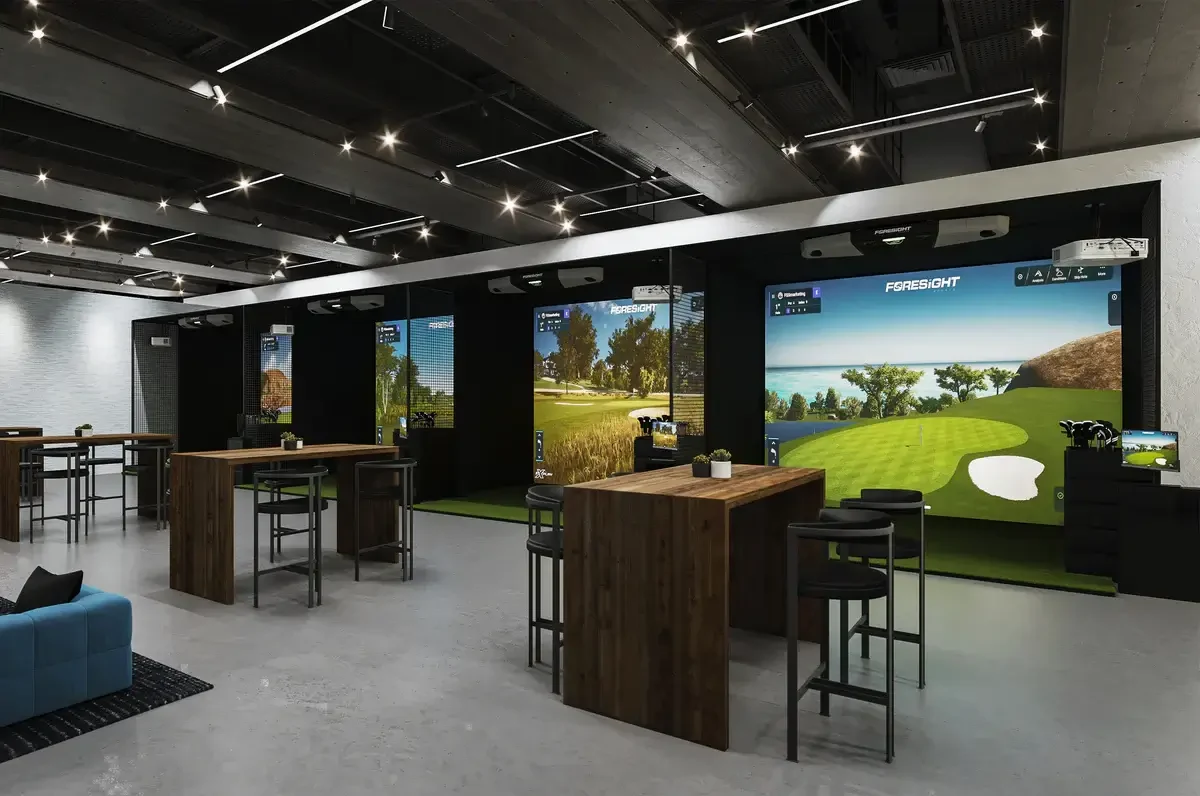 Commercial golf simulator venue with multiple bays, seating and overhead lighting